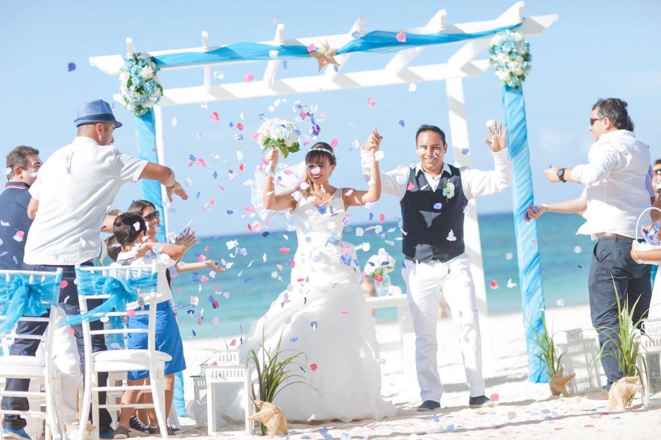 pareja de novios en ceremonia de matrimonio en la playa en punta cana la novia lleva un Vestido de tela organza corte semi trompeta