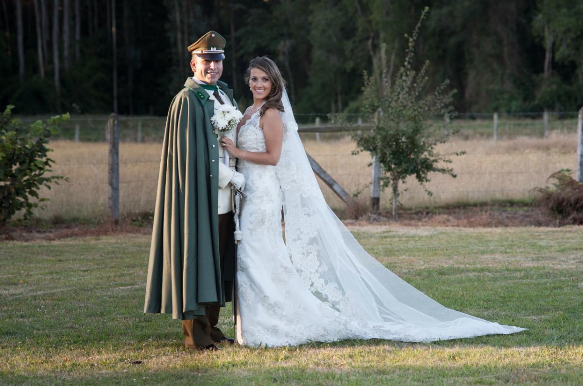pareja de novios en su casamiento militar hombre uniformado vestido con capa y traje de gala oficial novia con su vestido con capa blanca al aire libre