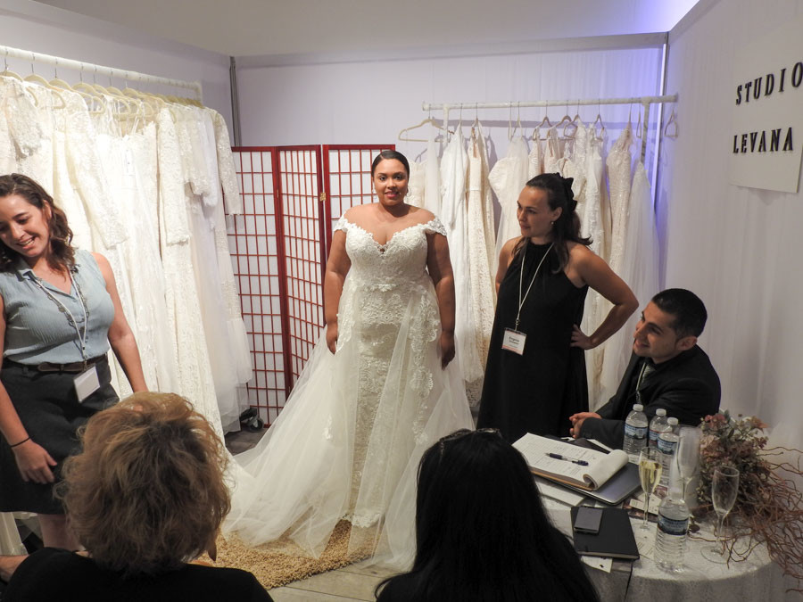 varias personas en el stand del NY bride fashion week en 2017 una modelo grande con vestido de novia xxl 