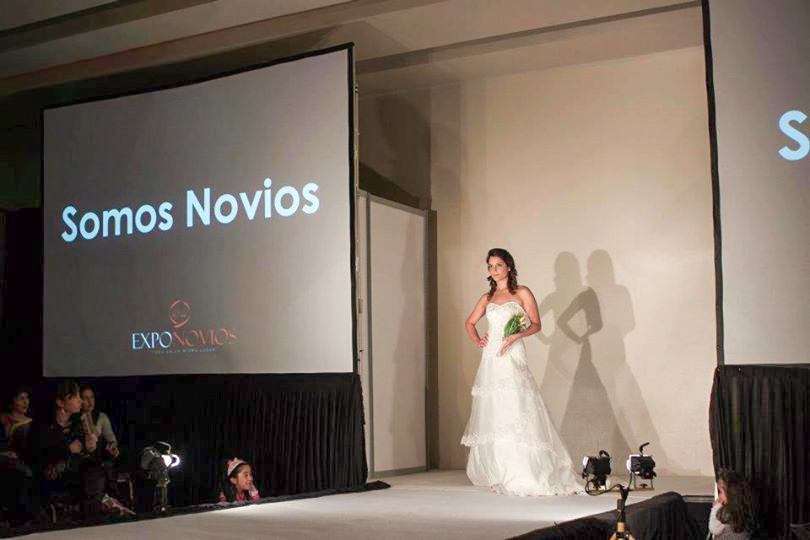 inicio del Desfile de Somos Novios en la ExpoNovios Temuco 2012 una modelo de pasarela con vestido de novia strapless y rama de tirar empezando a desfilar